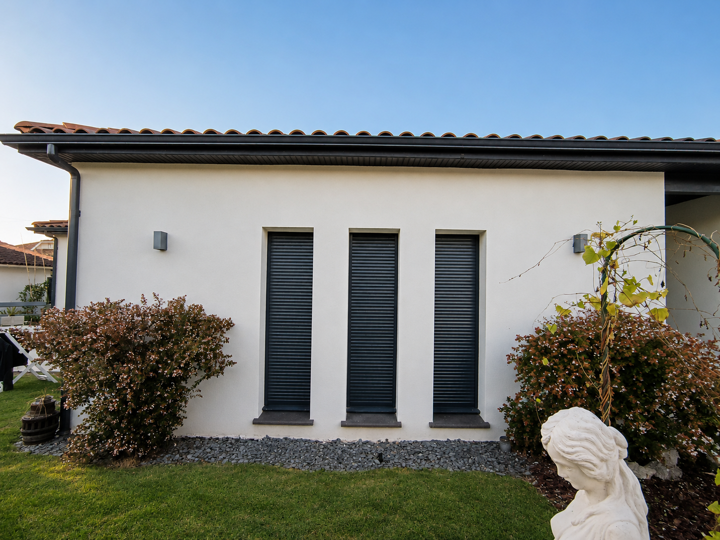 Volets roulants aluminium anthracite sur une façade blanche contemporaine